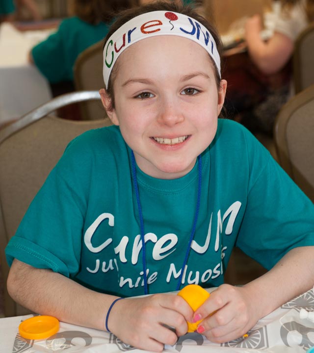 Girll with Cure JM headband sitting at table